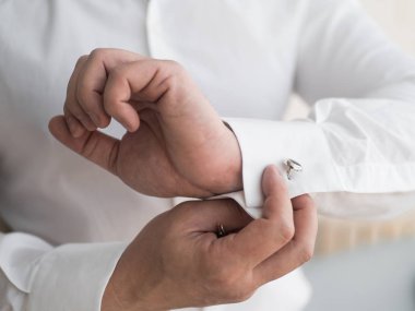 Damat şık kol düğmeleri takar. Yakın çekim..