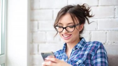 Evde cep telefonuyla konuşan neşeli genç bir kadın..