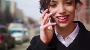 Mutlu, gülümseyen, neşeli, ironik kız cep telefonu kullanarak o heyecanlı bir konuşma vardır. Yakın çekim, açık, gerçek zamanlı, doğal ışık, soğuk sezon, yaşam biçimi.