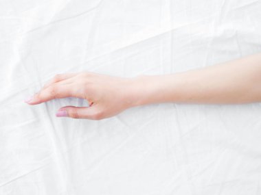 yatağın üstünde el. Beyaz çarşaflar. yatak odası.
