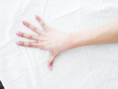 yatağın üstünde el. Beyaz çarşaflar. yatak odası.