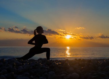 Plajda sakinlik ve yoga konsepti. Sahilde yoga yapan bir kadının silüeti..