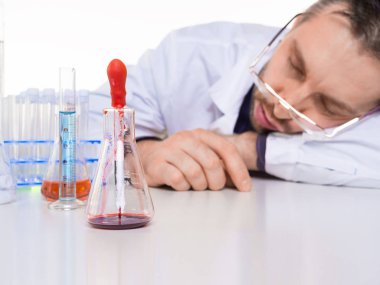 Laboratuvarda uyuyan bitkin bir bilim adamı. Laboratuar temalı bilim ve deney.