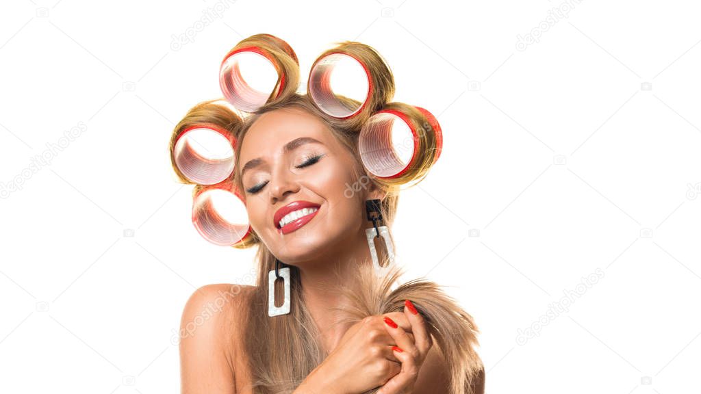 Happy young woman with hair curlers on her head isolated on white.
