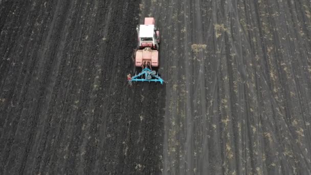 Zicht vanuit de lucht: trekker met een ploeg die het veld bebouwt. Landbouwconcept — Stockvideo