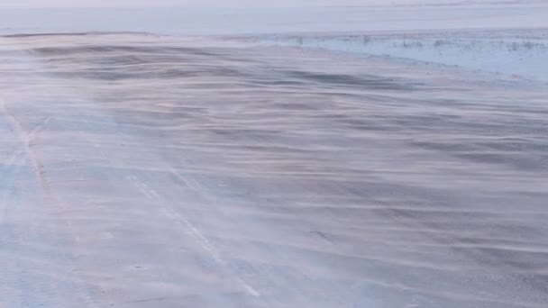 Viento soplando nieve en un camino rural en un día helado de invierno — Vídeo de stock