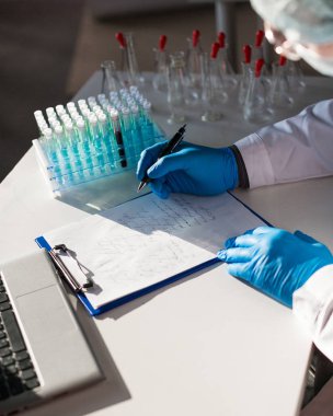 Laboratuvardaki bir doktorun elleri. Anti-virüs aşısı araştırması için not al.