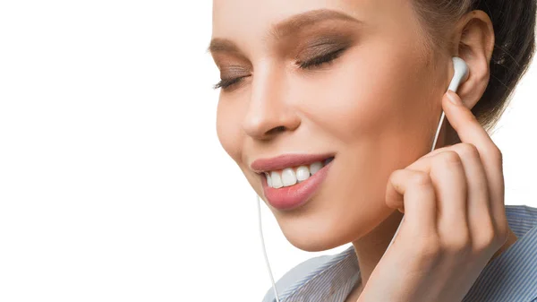 Retrato de uma jovem sorridente ouvindo a música através de fones de ouvido . — Fotografia de Stock