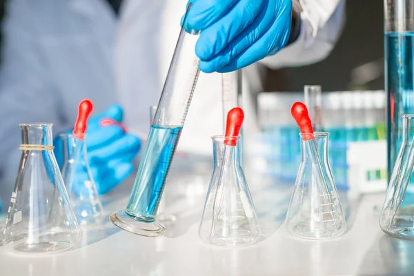 Un médico en un laboratorio está trabajando en una vacuna contra el virus. Vista cercana de un médico poniendo un matraz sobre una mesa — Foto de Stock