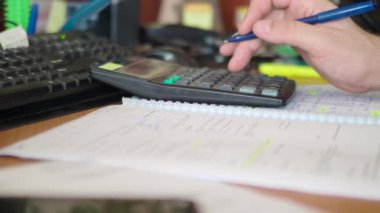 Modern office stillife. Close up footage - male hand works on calculator and make notes