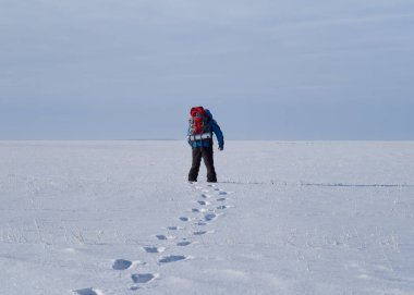 Sırt çantalı yalnız bir adam kar çölünde yürüyor..
