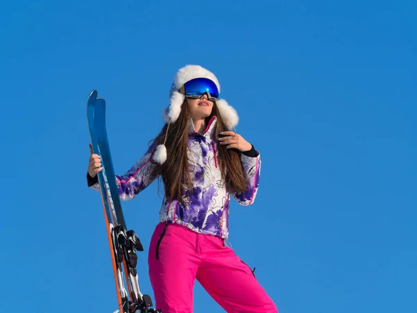 Χειμερινό πορτραίτο μιας γυναίκας με ένα σκι σε μια βουνοκορφή πάνω από το μπλε φόντο του ουρανού. Έννοια ενεργού τρόπου ζωής — Φωτογραφία Αρχείου