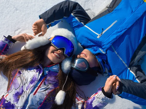 Αγαπημένο ζευγάρι βρίσκεται στο χιόνι ενώ χαλαρώνει σε μια πλαγιά σκι σε ένα χιονοδρομικό κέντρο. — Φωτογραφία Αρχείου