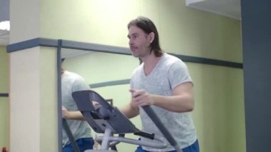 Spor salonunda orta yaşlı bir adam. Kardiyo çalışması.