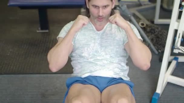 Muž v tělocvičně. Pumpování trupu - cvičení břicha. Horní pohled. — Stock video