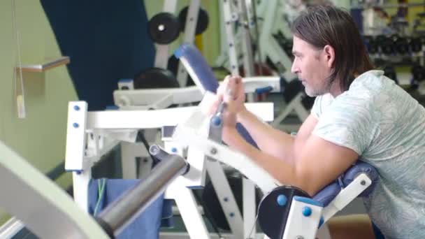 Schweres Training in der Bizepsmaschine. Mann mittleren Alters trainiert im Fitnessstudio. — Stockvideo