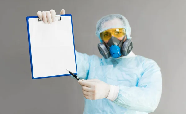 Lekarz w respiratorze i odzieży ochronnej pokazuje papier z diagnozą. — Zdjęcie stockowe
