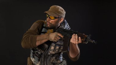 Yandan bakan silahlı bir paralı asker. Karanlık bir arkaplanda fotoğraf.