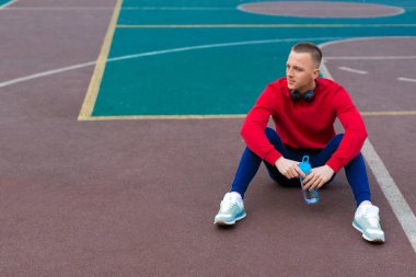 Spor sahasında antrenman yapan genç bir adam dinleniyor..