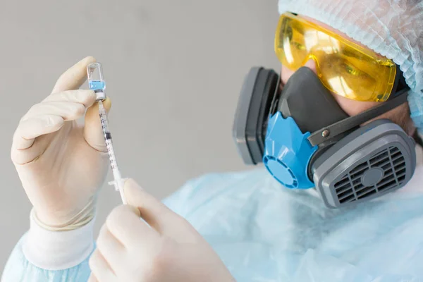 Närbild av en läkare i en skyddsmask som injicerar ett vaccin mot en sjukdom i en spruta. — Stockfoto