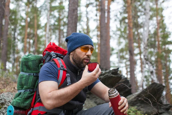 Boissons touristiques masculines thé dans la forêt rocheuse . — Photo