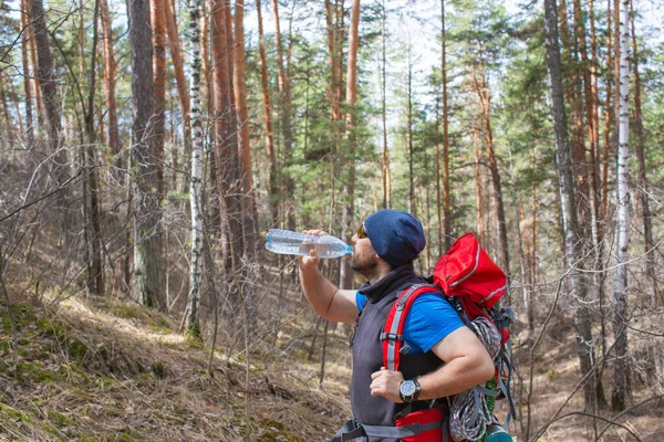 Toerist drinkt water uit een fles in het bos. — Stockfoto