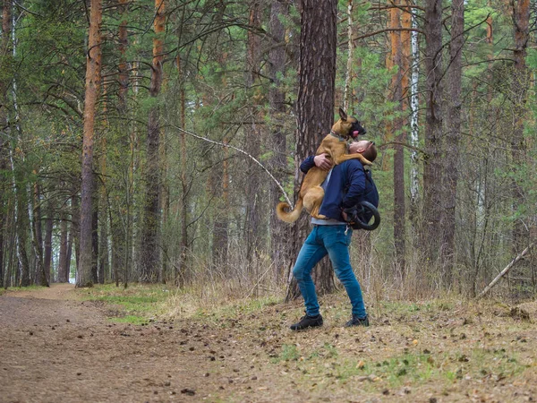 Um homem está a brincar na floresta com o seu cão. Animais de estimação do amor e conceito de amizade . — Fotografia de Stock