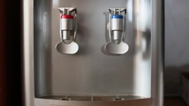 İnsan eli, su haznesinden soğuk suyu bardağa dolduruyor..