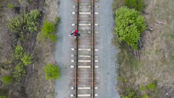 バックパック付きの観光客は鉄道のレールに乗ります。バランスと落下しないようにしてください。上からの眺め. — ストック動画