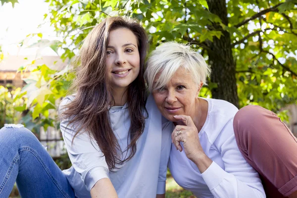 Ładny Mama i córka skonsultować się z laptopa pod drzewem w autum — Zdjęcie stockowe