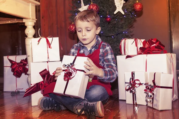 Прекрасный маленький мальчик открывает рождественские подарки — стоковое фото