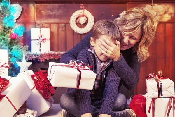 Прекрасный маленький мальчик открывает рождественские подарки с ее матерью — стоковое фото