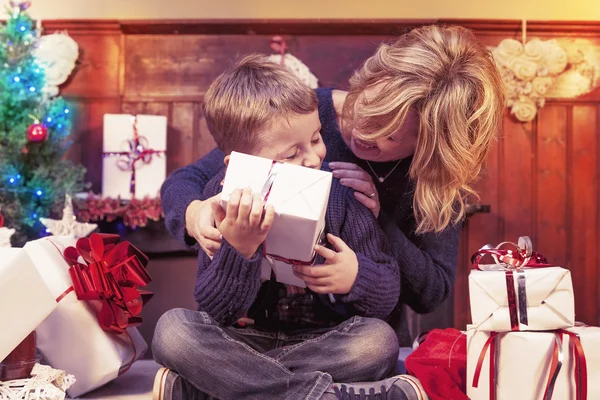 Прекрасный маленький мальчик открывает рождественские подарки с ее матерью — стоковое фото