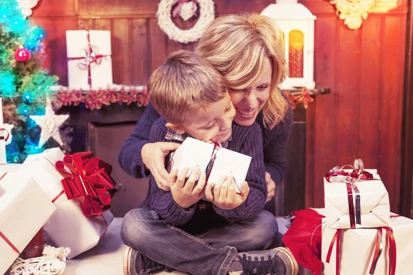 Szép kisfiú édesanyja karácsonyi ajándékok nyitja meg — Stock Fotó