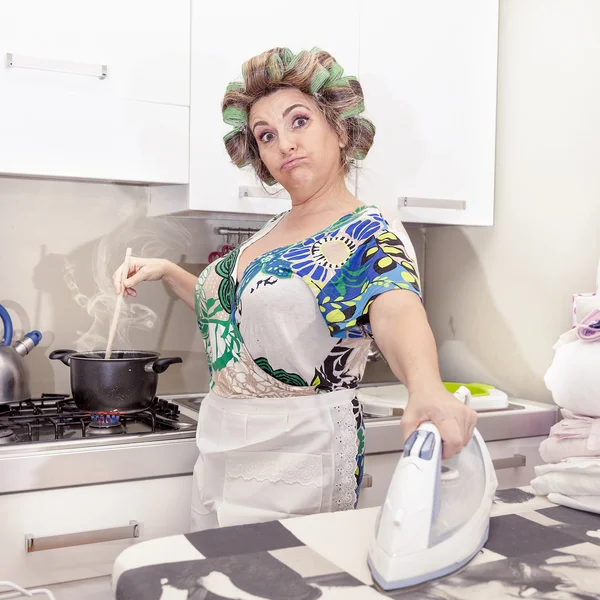 Vacker mogen kvinna med papiljotter stryka kläder hemma — Stockfoto