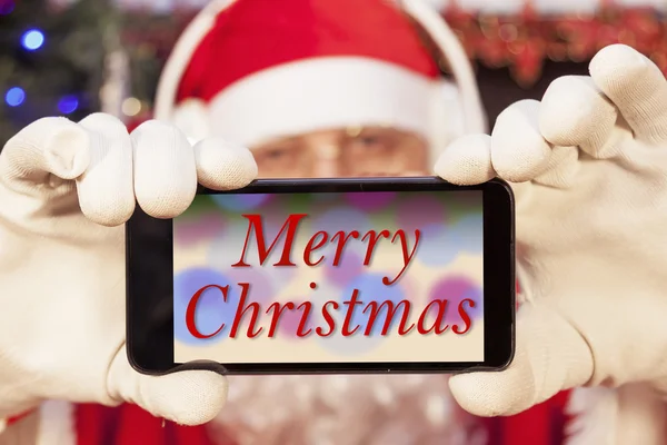 Santa claus pokazuje kartki świąteczne na wyświetlaczu smartfona — Zdjęcie stockowe