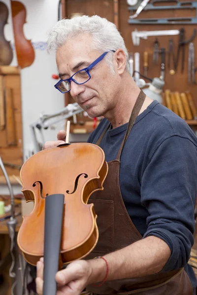 Portrait of mature violin maker while testing the violins in his — Stock Photo, Image