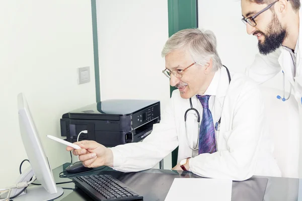 Doctors examining medical results to computer — Stock Photo, Image