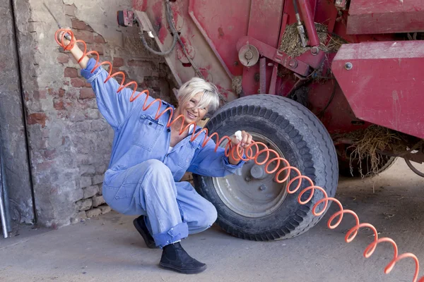 Hembra madura mecánica infla el neumático del tractor — Foto de Stock