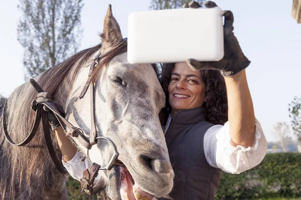 Jinete se toma un selfie con su caballo a las carreteras del campo en —  Fotos de Stock