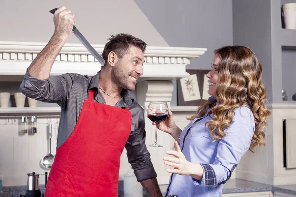 Genç koca Şakalar bir bıçak ile mutfakta karısıyla — Stok fotoğraf