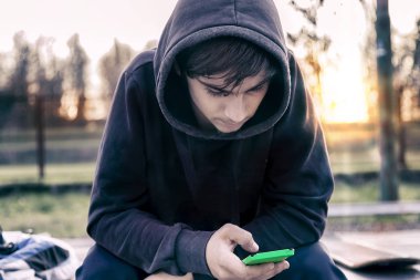 Genç Yetişkin kaykaycı oturan bir ileti yazar akıllı telefon