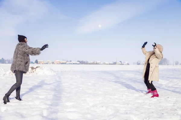 Máma a dcera hrát tahat sníh v zemi — Stock fotografie