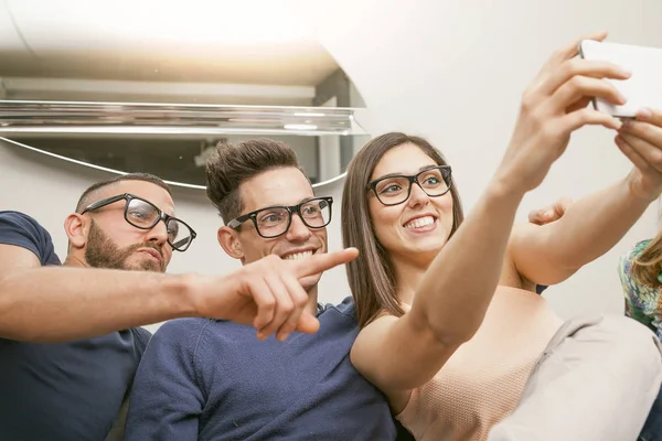 Skupina přátel na gauči trvá selfie velmi zábavným způsobem — Stock fotografie