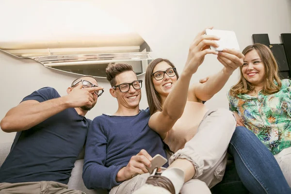 Grupo de amigos no sofá leva uma selfie de uma forma engraçada — Fotografia de Stock