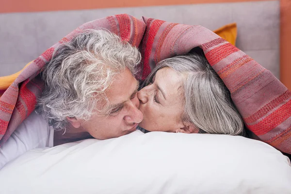 Взрослая пара целуется в постели перед сном — стоковое фото