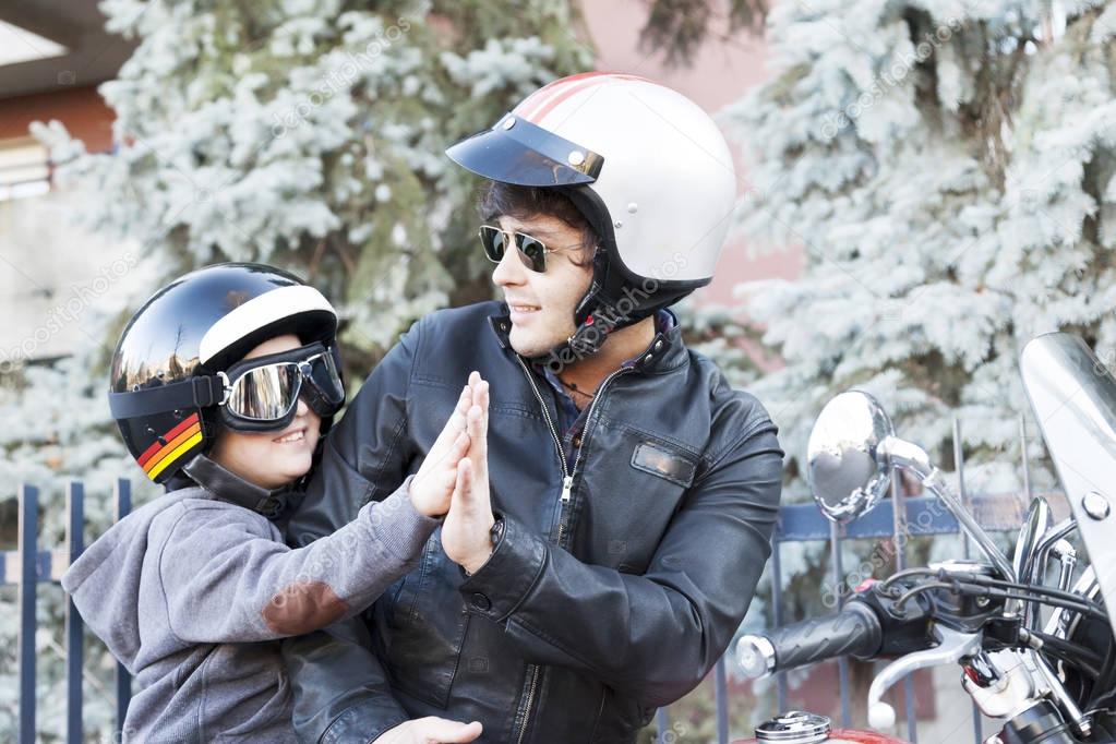 father and son motorcyclists high five
