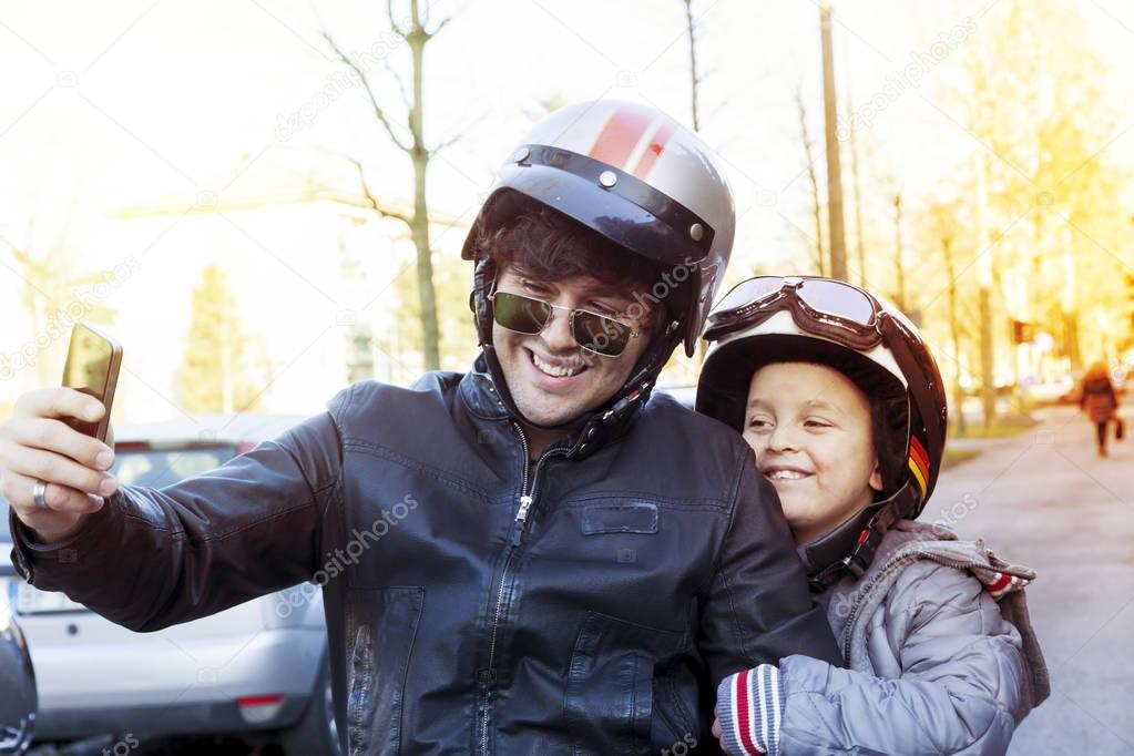 father and son motorcyclists take a selfie on the road