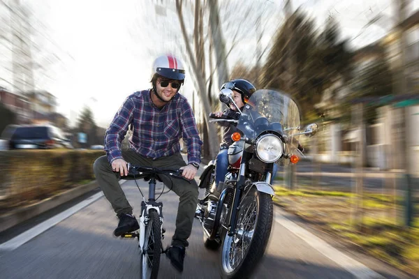 Adultos jovens simulam uma corrida simulada entre moto e bicicleta — Fotografia de Stock