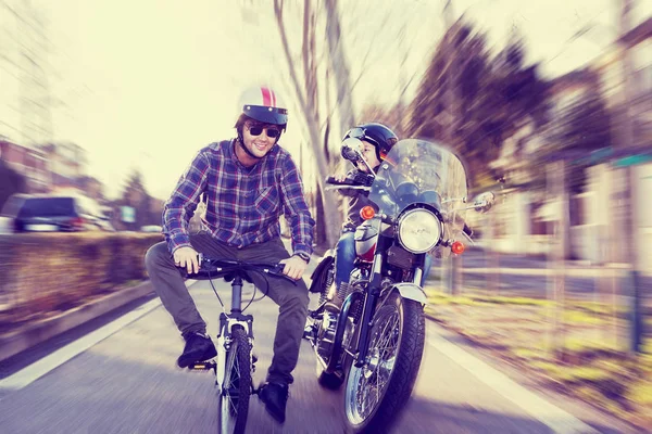 Adultos jovens simulam uma corrida simulada entre moto e bicicleta — Fotografia de Stock